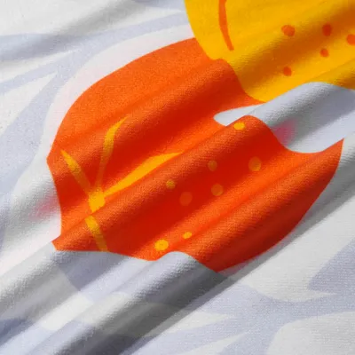 Close-up of a custom printed towel with a vibrant orange and yellow design on a white background, suggesting premium quality and a summery feel.