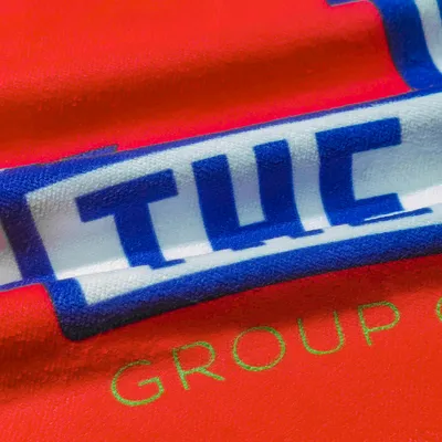 Custom printed towels with a bold 'TWC GROUP' logo on a vibrant red fabric, showcasing the detail and quality of personalized towels.